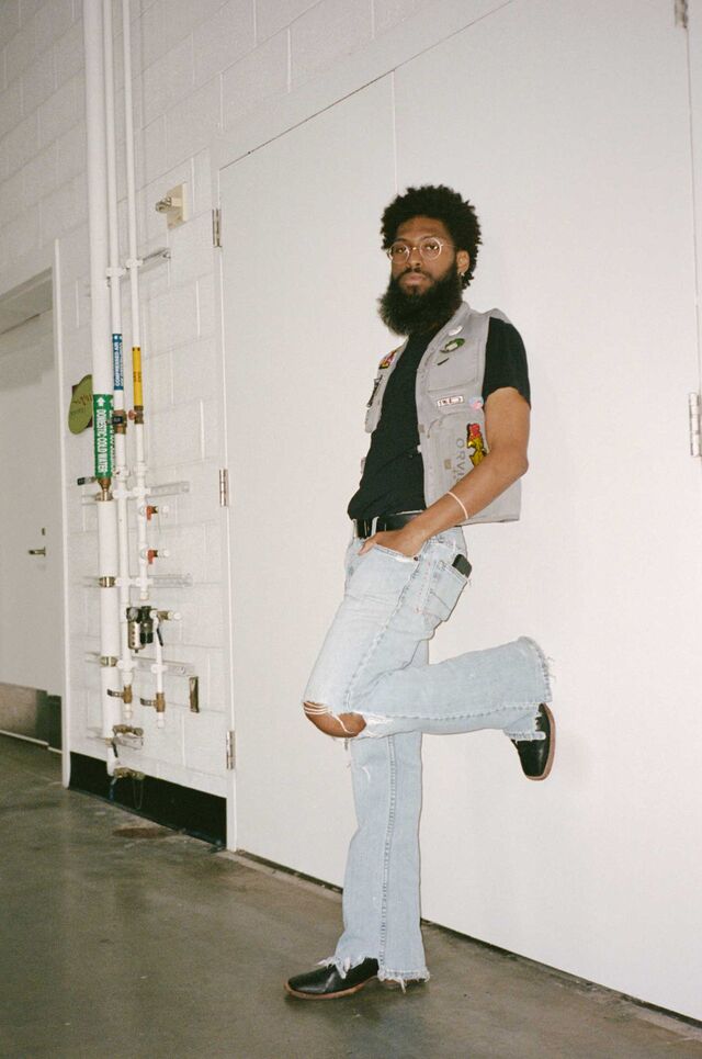 Noah Abrams leans against a wall, wearing vintage clothing
