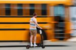 A scooter rider zooms past a parked school bus as he rides along the beach in San Diego, California.