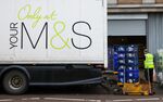 An employee pushes crates of goods into a loading bay outside a Marks &amp; Spencer Group store in the UK