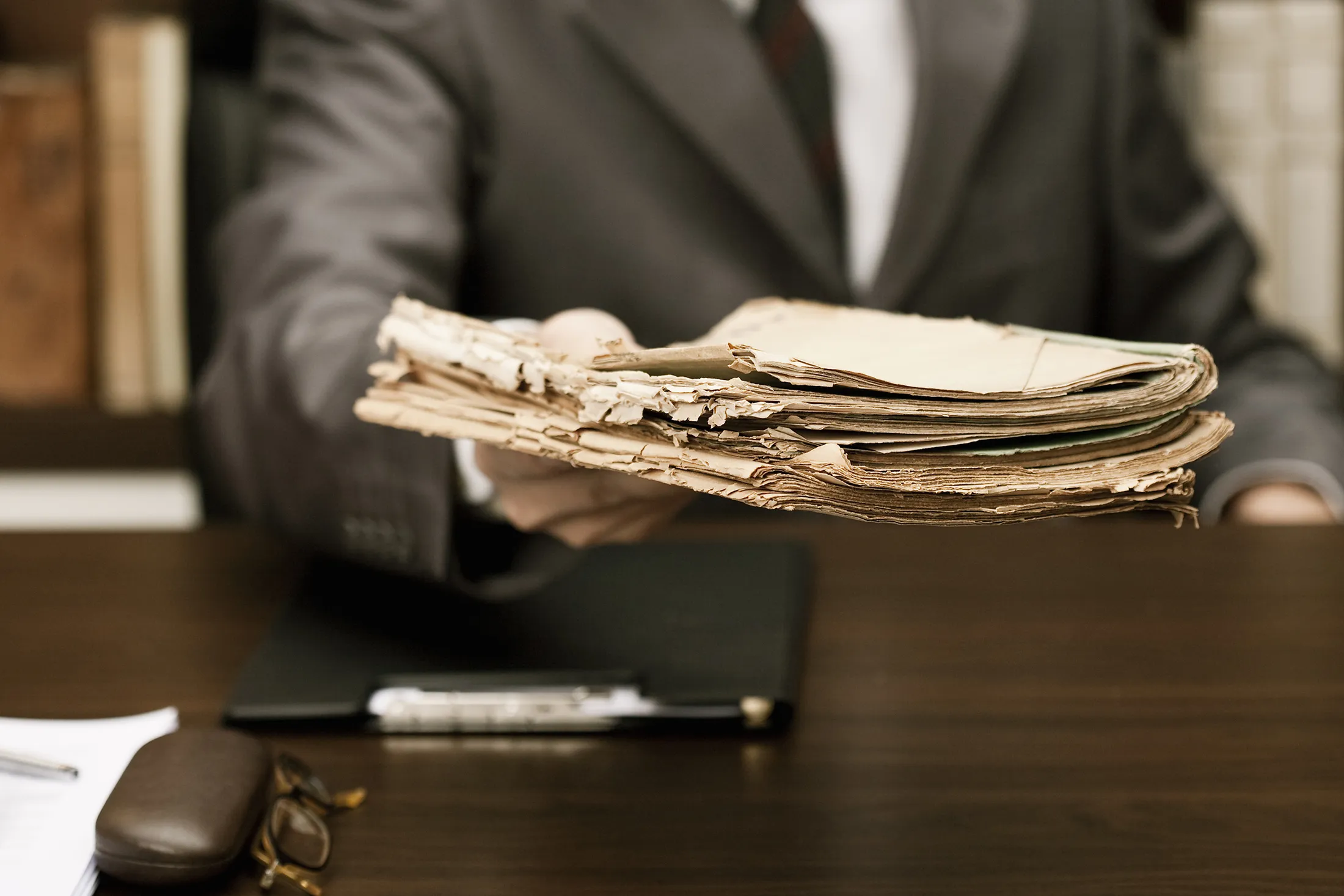 Man in suit handing over old documents