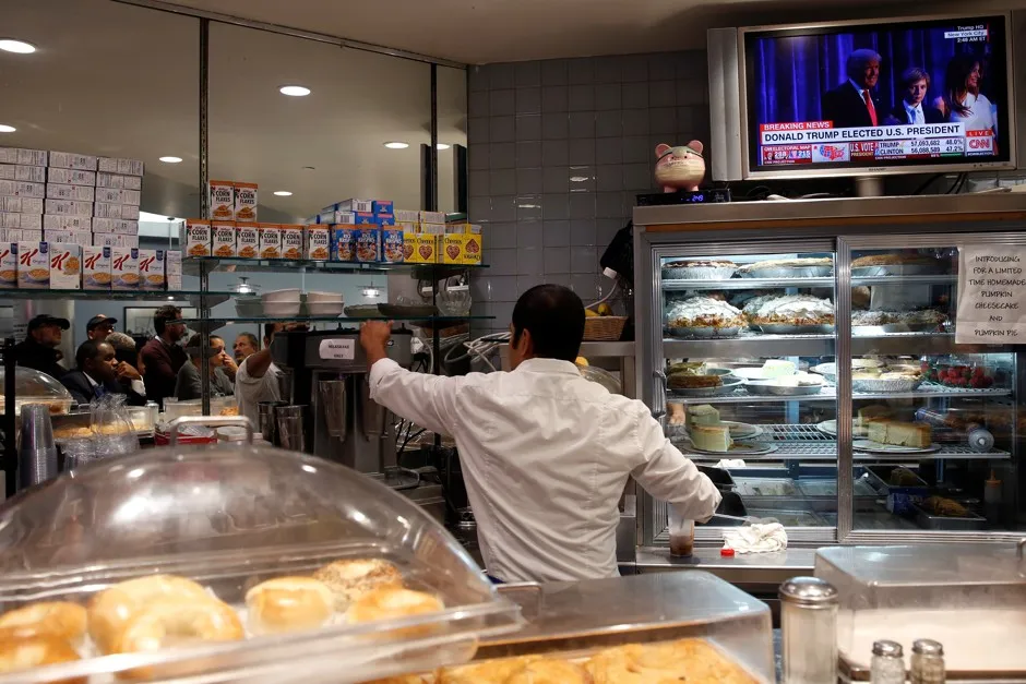A worker serves customers at a New York diner as the result of the 2016 U.S. presidential election is shown on a TV screen.