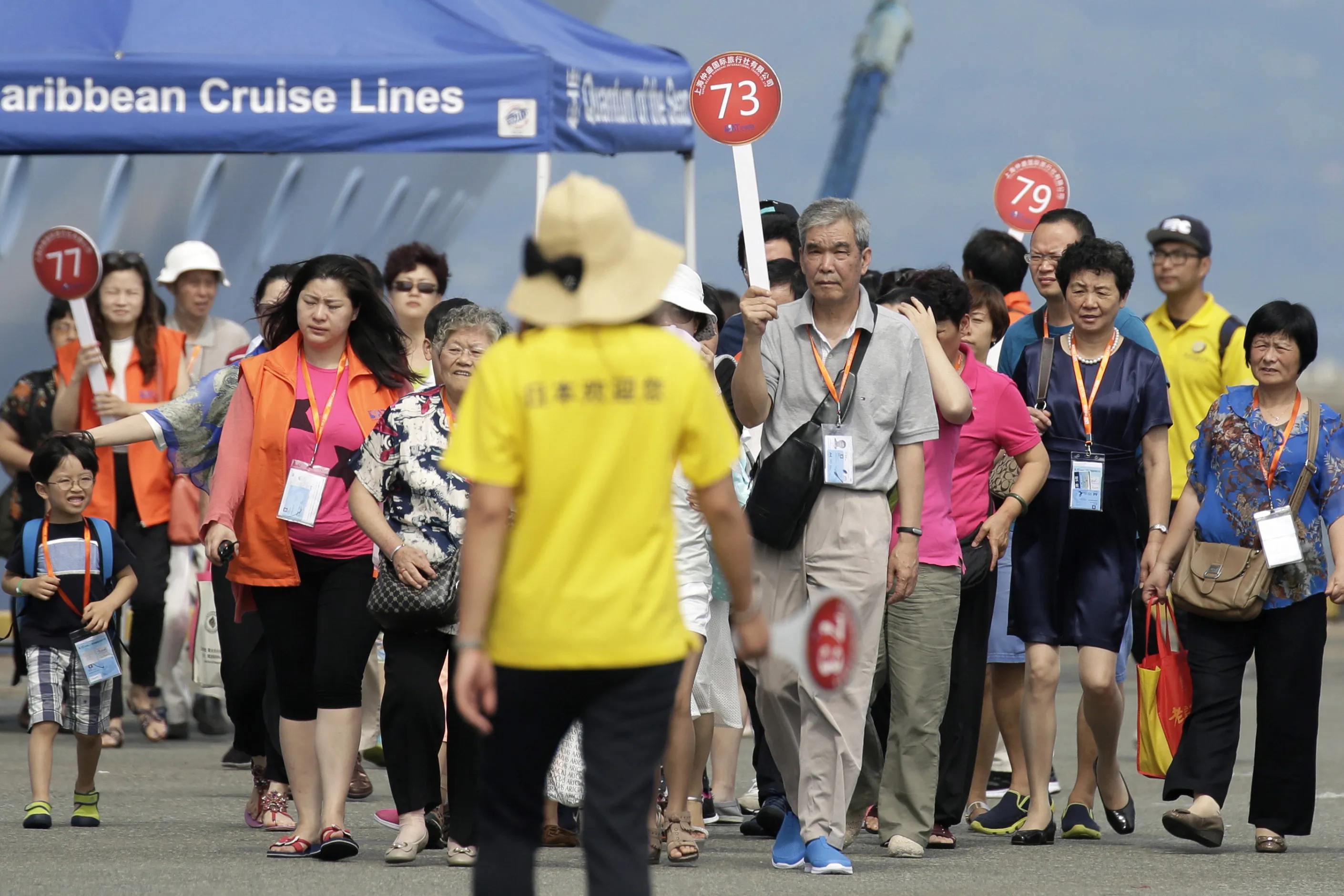 Chinese tourists walk though a pier after descending from the Quantum of the Seas cruise ship, operated by Royal Caribbean Cruises Ltd.'s cruise line brand Royal Caribbean International (RCI), upon arrival at the Port of Hakata in Fukuoka, Japan. Photographer: Kiyoshi Ota/Bloomberg
