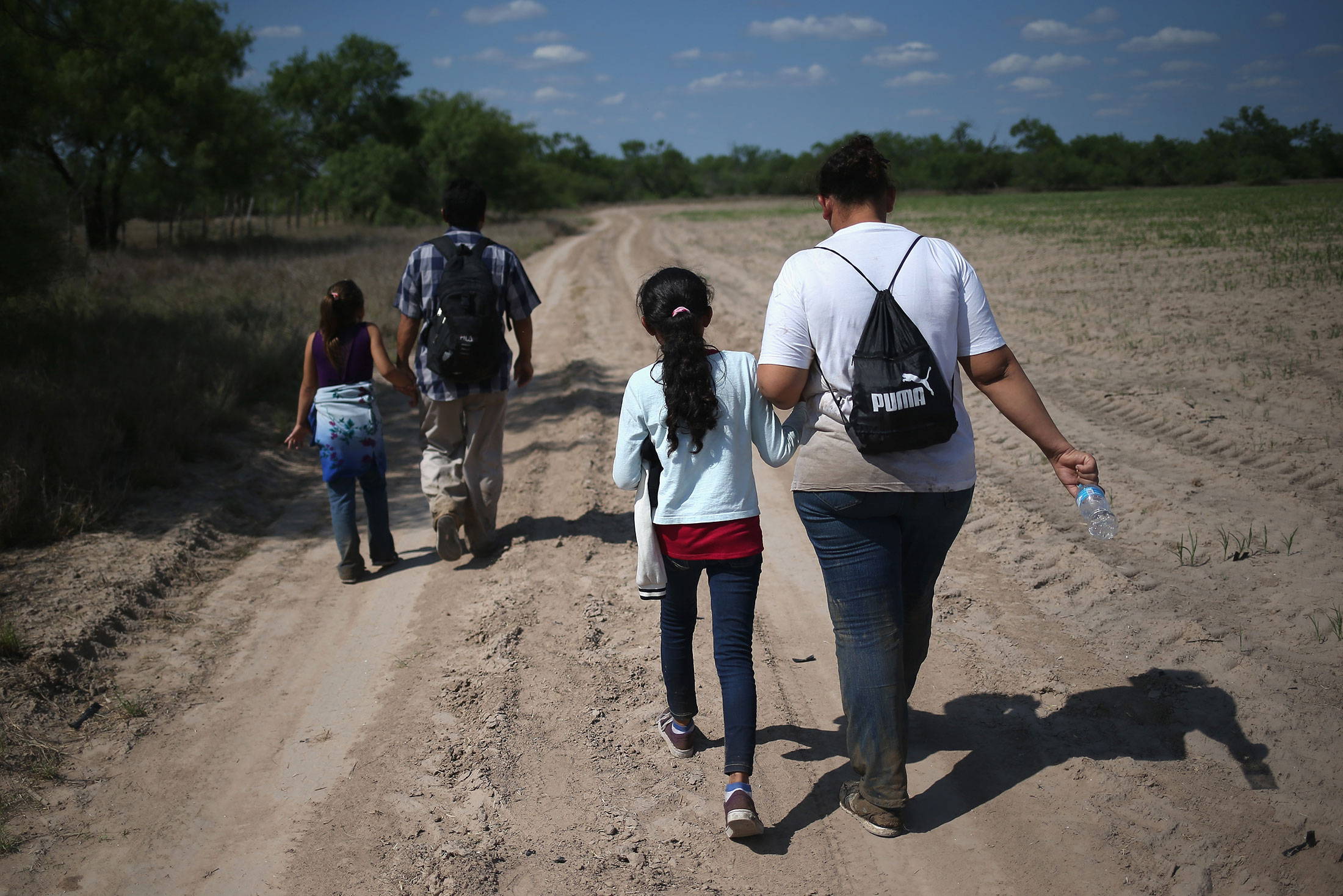 Central American immigrant families walk through the countryside after crossing from Mexico into the United States to seek asylum on April 14, 2016 in Roma, Texas.
