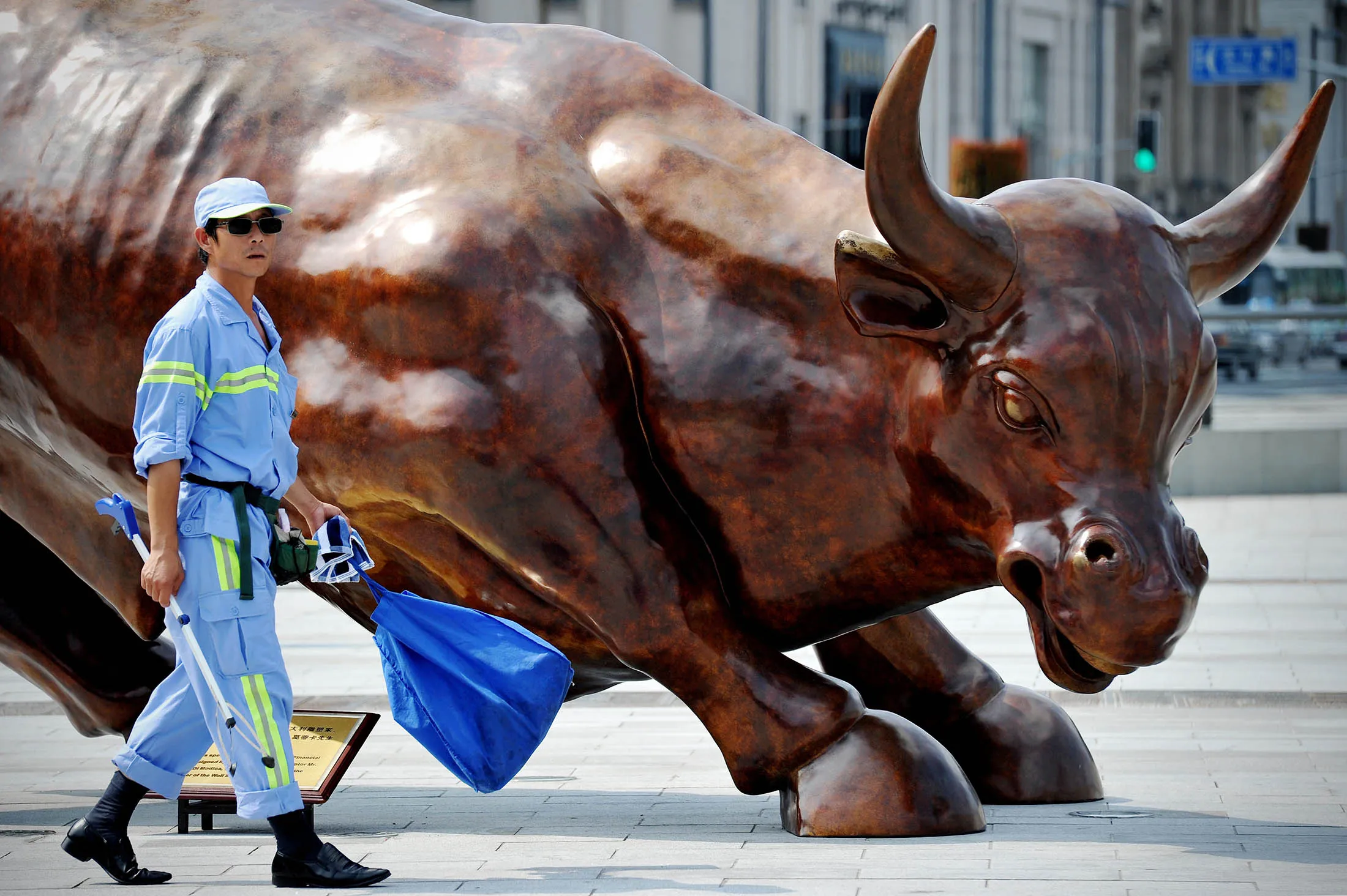 A Chinese worker walks past the city's charging bull statue in Shanghai, China.
