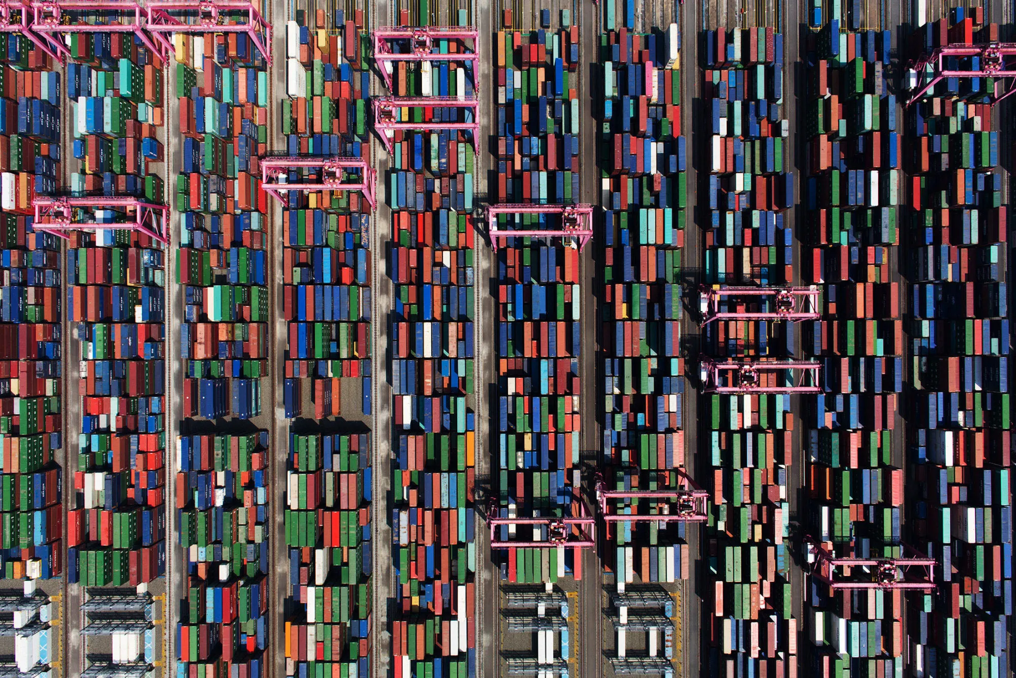 Shipping containers sit stacked among gantry cranes in this aerial photograph taken above the BNCT Co. container terminal at Busan New Port in Busan, South Korea, on Thursday, July 30, 2015. South Korea is scheduled to release trade figures on Aug. 1.
