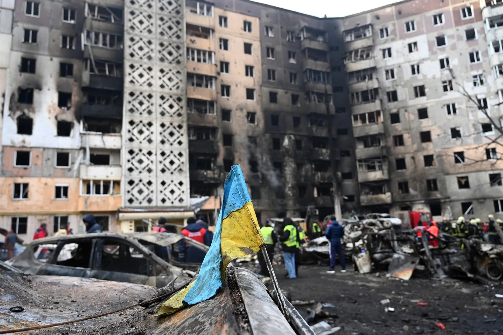 A Ukrainian flag attached to a burned car at the site of a damaged building following a Russian air strike in Ternopil.
