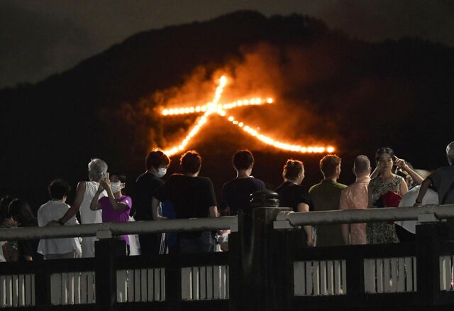 Onlookers gaze at a huge bonfire that was lit on a mountain during the Daimonji Festival in Kyoto on Aug. 16, 2022.