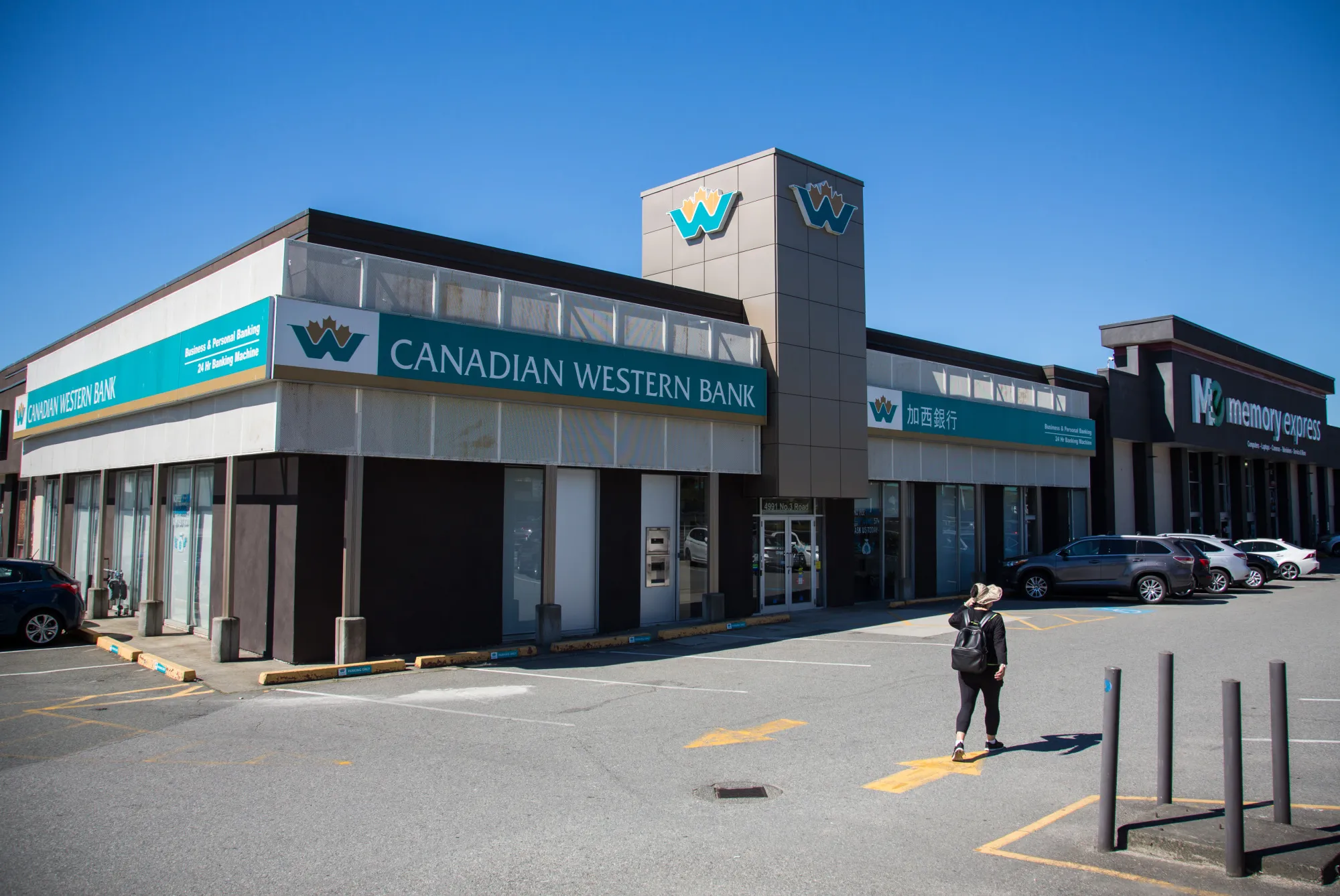 A pedestrian passes in front of a Canadian Western Bank branch in Richmond, British Columbia, Canada.