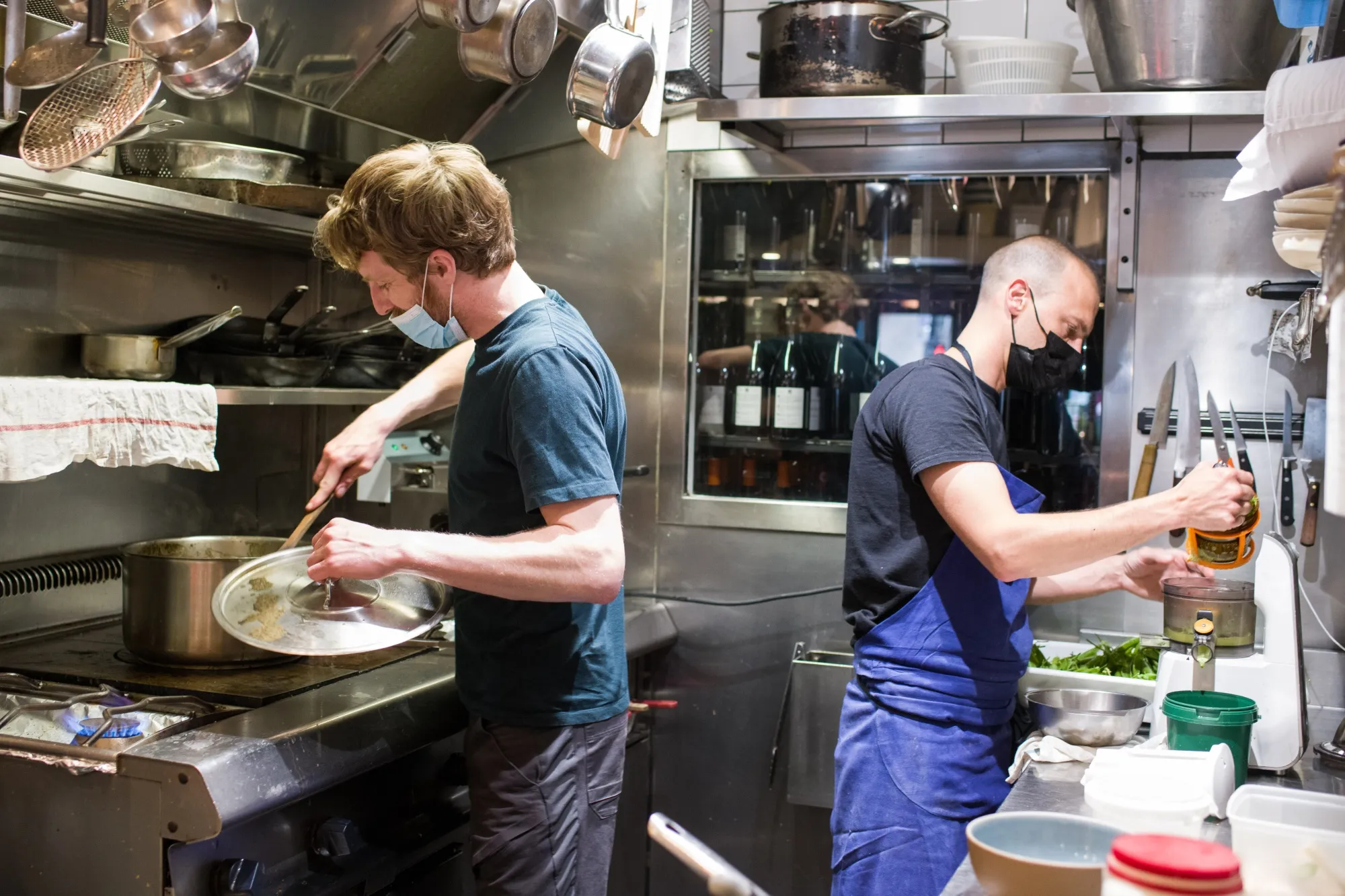 Chefs wearing protective masks cook in the kitchen of a restaurant in Paris, France, on Wednesday, May 19, 2021. Europe is waking up from the pandemic with cafes in Paris, gelato vendors in Rome and beer gardens in Bavaria reopening, a major test for the regions recovery in health and economic terms.