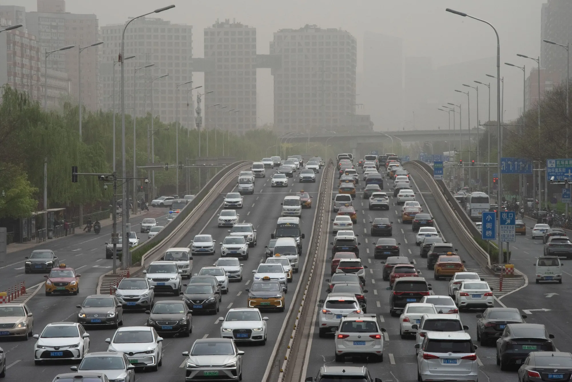 Vehicles travel on a road shrouded in smog during a sandstorm warning in Beijing, China, on Thursday, April 13, 2023.&nbsp;