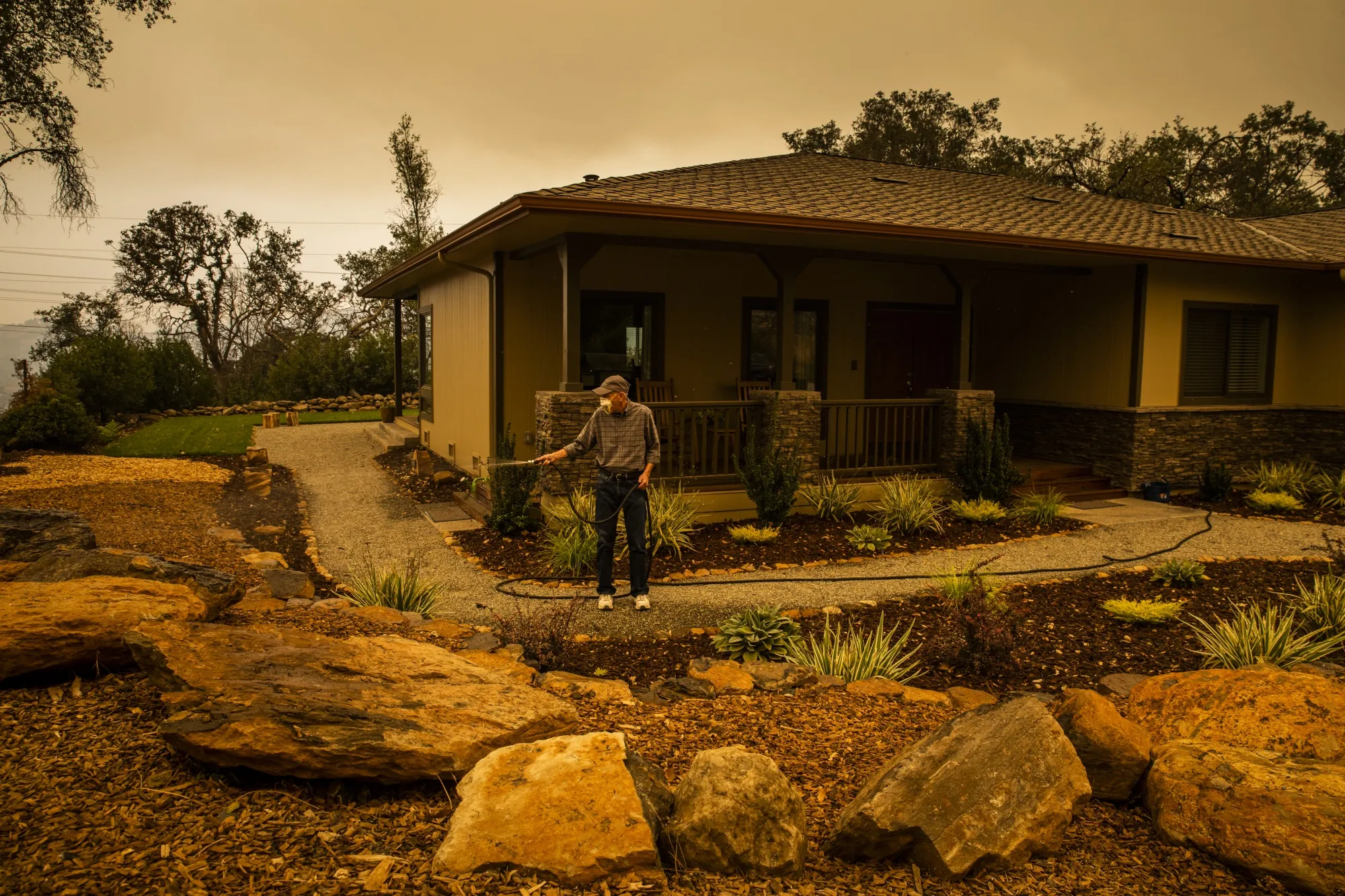 Richard Hicks hoses down the grounds in front of his home in Santa Rosa, Calif., in preparation for evacuating&nbsp;during the Glass Fire on Sept. 28.