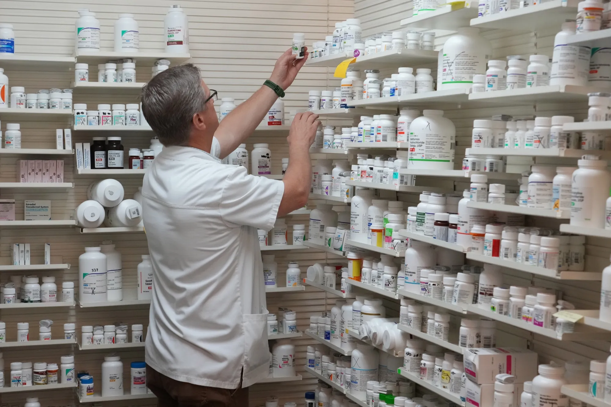 A pharmacist pulls a drug from a shelf inside a pharmacy in Provo, Utah.