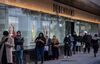 Shoppers wearing protective face masks queue outside the Debenhams Plc Oxford Street department store marked for closure in London, U.K., on Saturday, Dec. 5, 2020. U.K. retail landlords are facing a hard reality: the rapid approval of a vaccine has come too late for thousands of their stores.