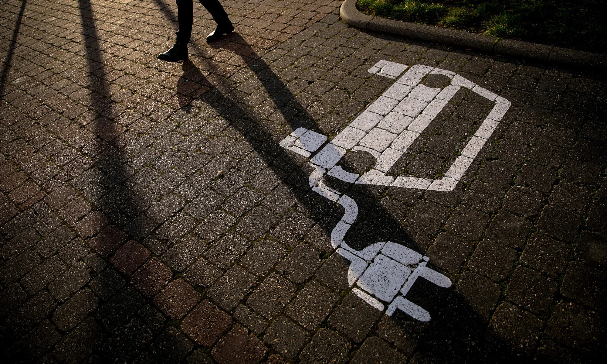 A pedestrian passes an empty electric vehicle charge point space in Gruenheide, Germany.