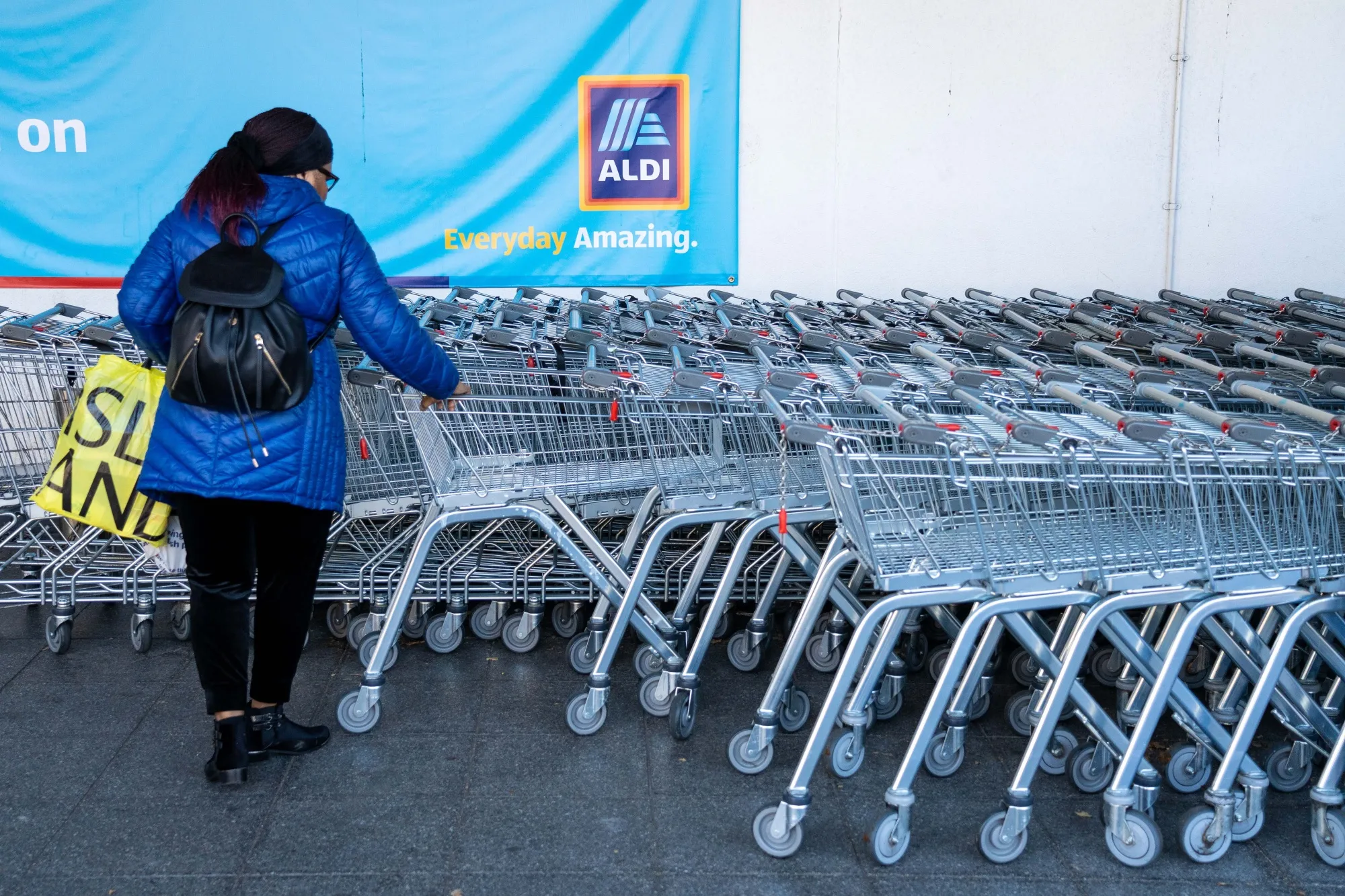 A customer collects a supermarket trolley outside an Aldi Stores Ltd. supermarket in Sheffield, UK.