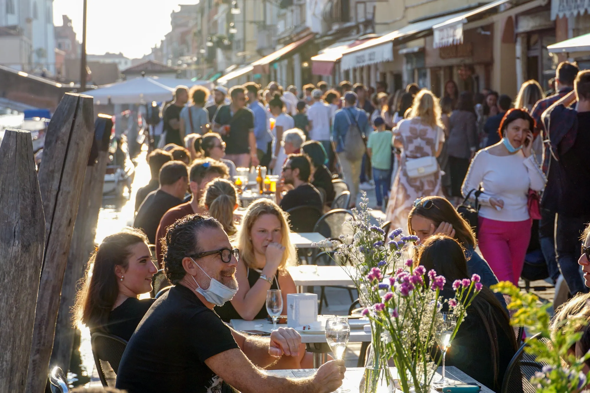 Tourists and Venetians sit at terraced tables of bars in Cannaregio district of Venice.