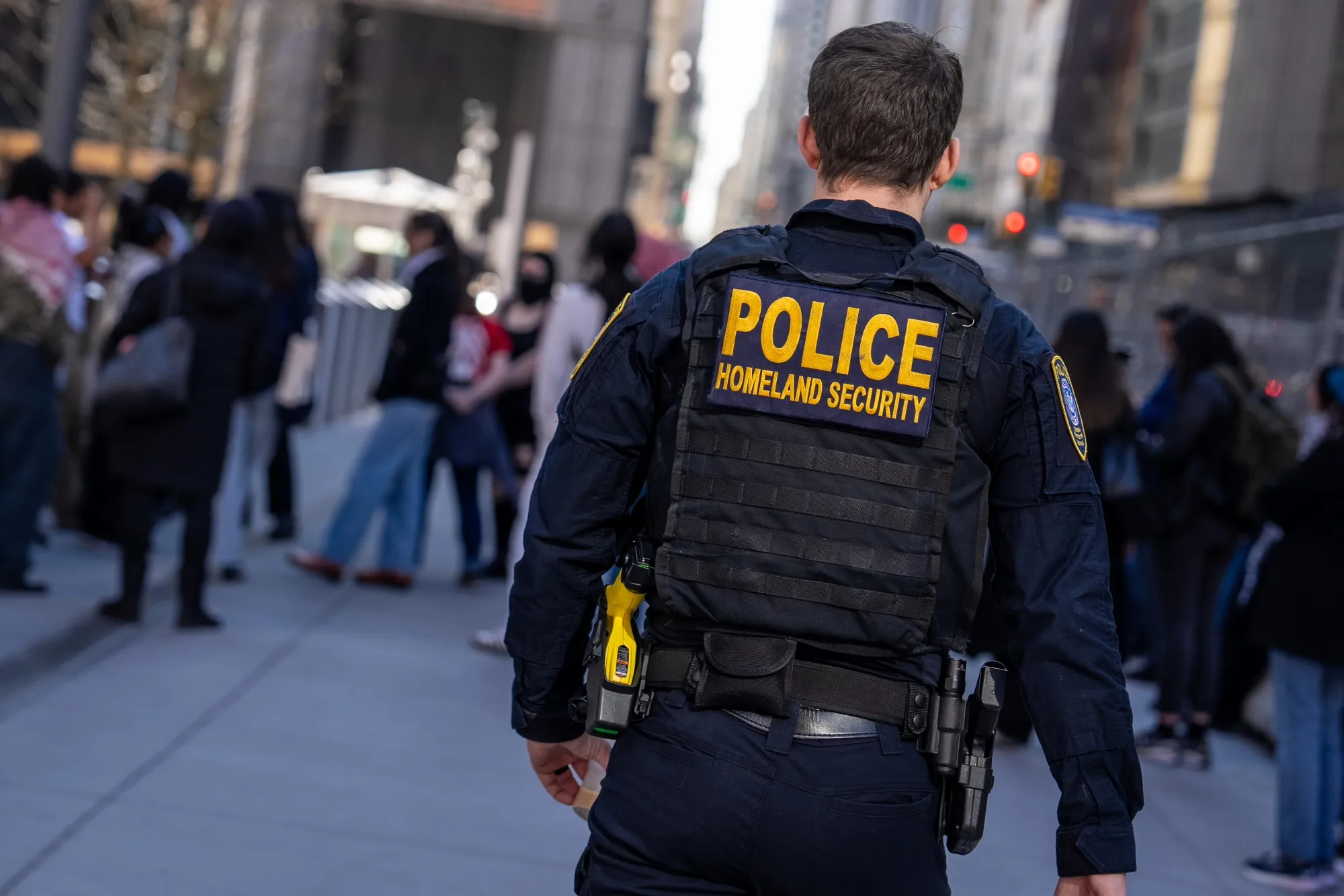 A Department of Homeland Security officer watches as protestors gather in New York City on March 10.&nbsp;