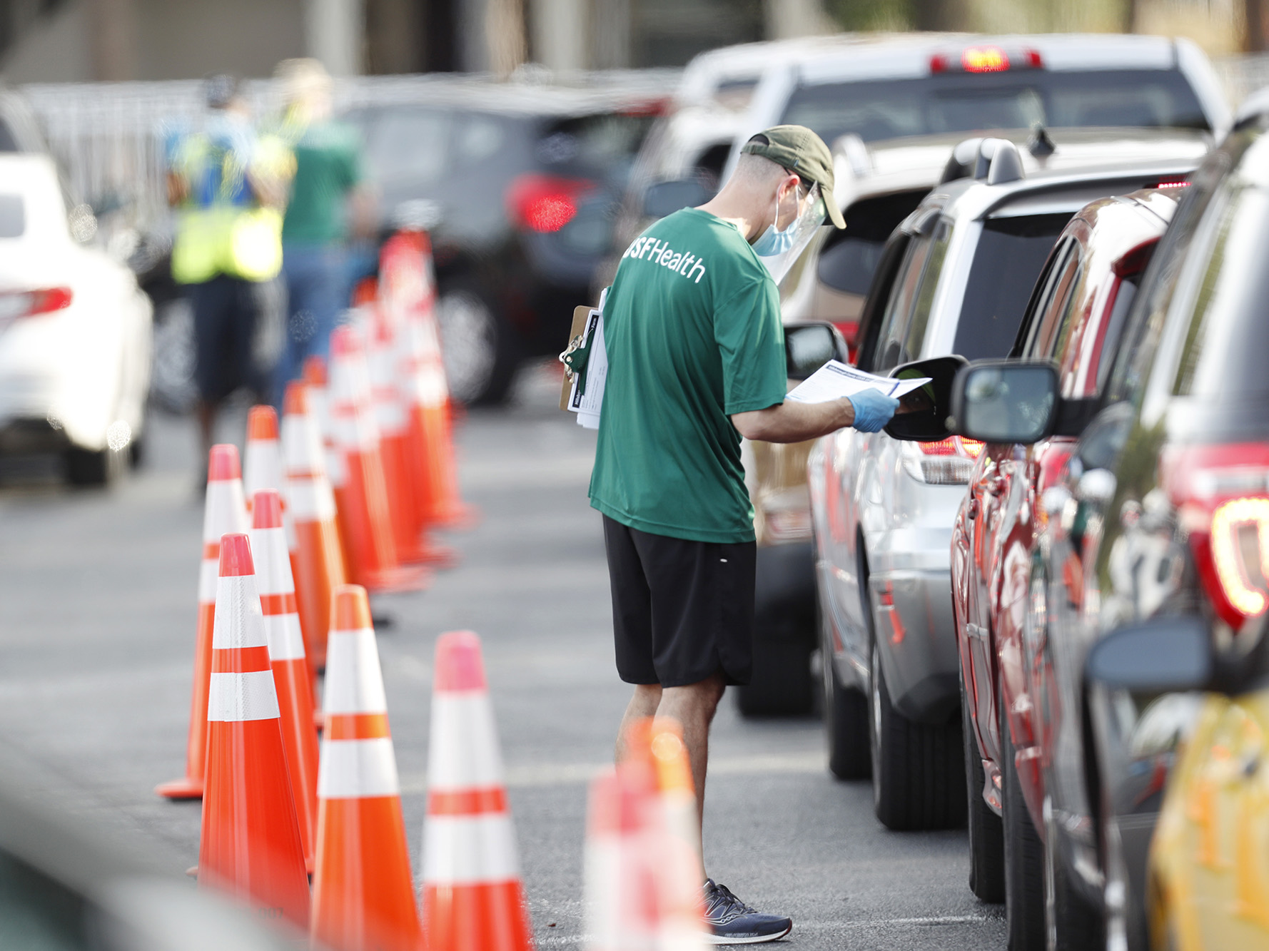 A University of South Florida (USF) Health administrator talks to a driver before they receive a coronavirus test at the Lee Davis Community Resource Center on June 25, 2020 in Tampa, Florida.