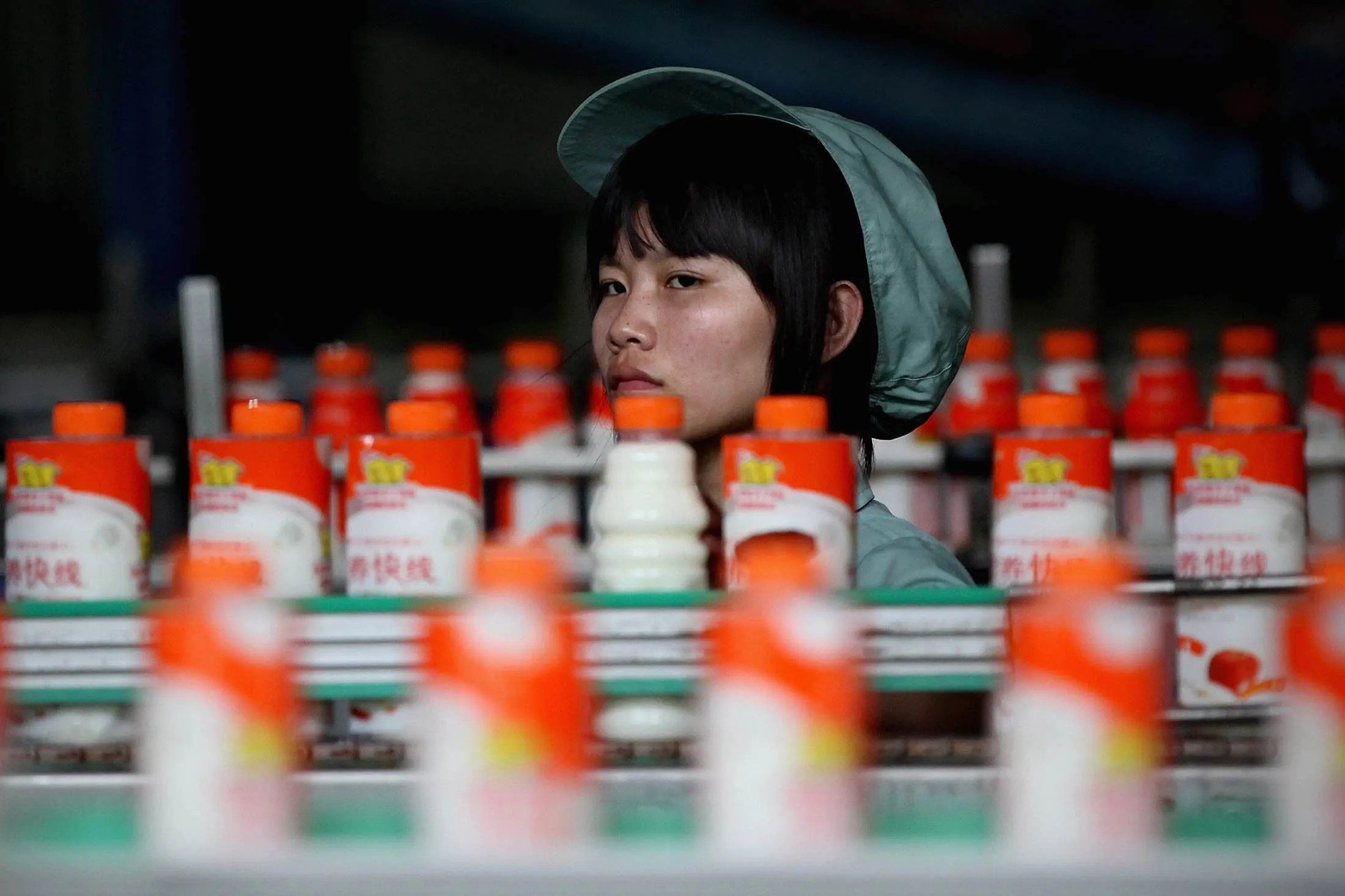 A worker watches bottles of a milk drink on a production line in Hangzhou, China.

