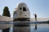 A reporter takes a smart phone photo of a mock up of the Crew Dragon spacecraft