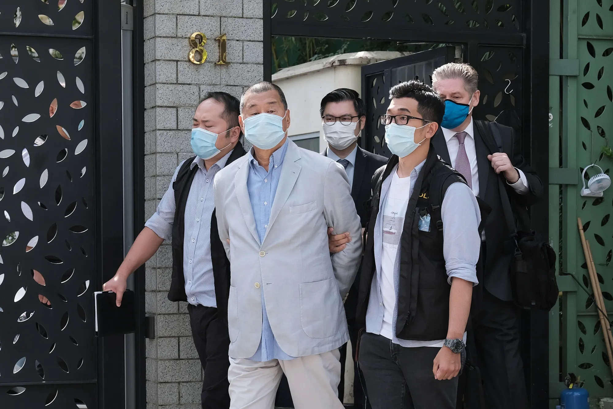 Jimmy Lai, second from left, is led away from his residence by law enforcement officials in Hong Kong, in 2020.
