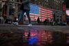 Pedestrians walk past an illuminated American flag in the Times Square area of New York.