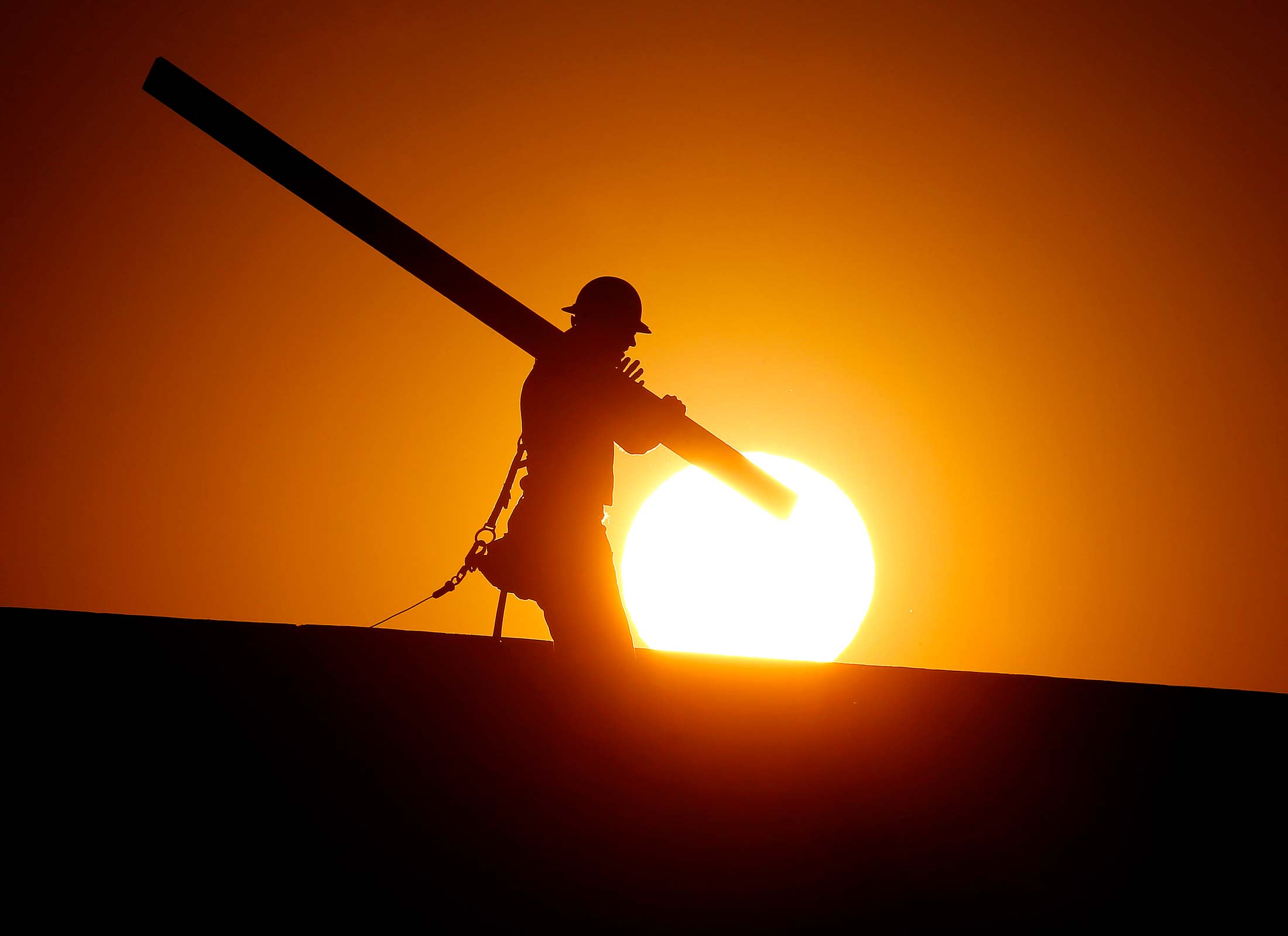 A home builder works at sunrise on Monday, June 20, in Gilbert, Arizona, in an effort to beat the rising temperatures.
