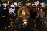 Demonstrators hold candles and blank signs during a protest in Beijing, China, on Nov. 27.