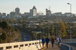 Pedestrians walk along a roadway back-dropped by commercial and residential buildings in the Sandton district of Johannesburg.