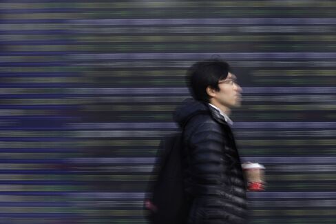 株価ボード前の歩行者