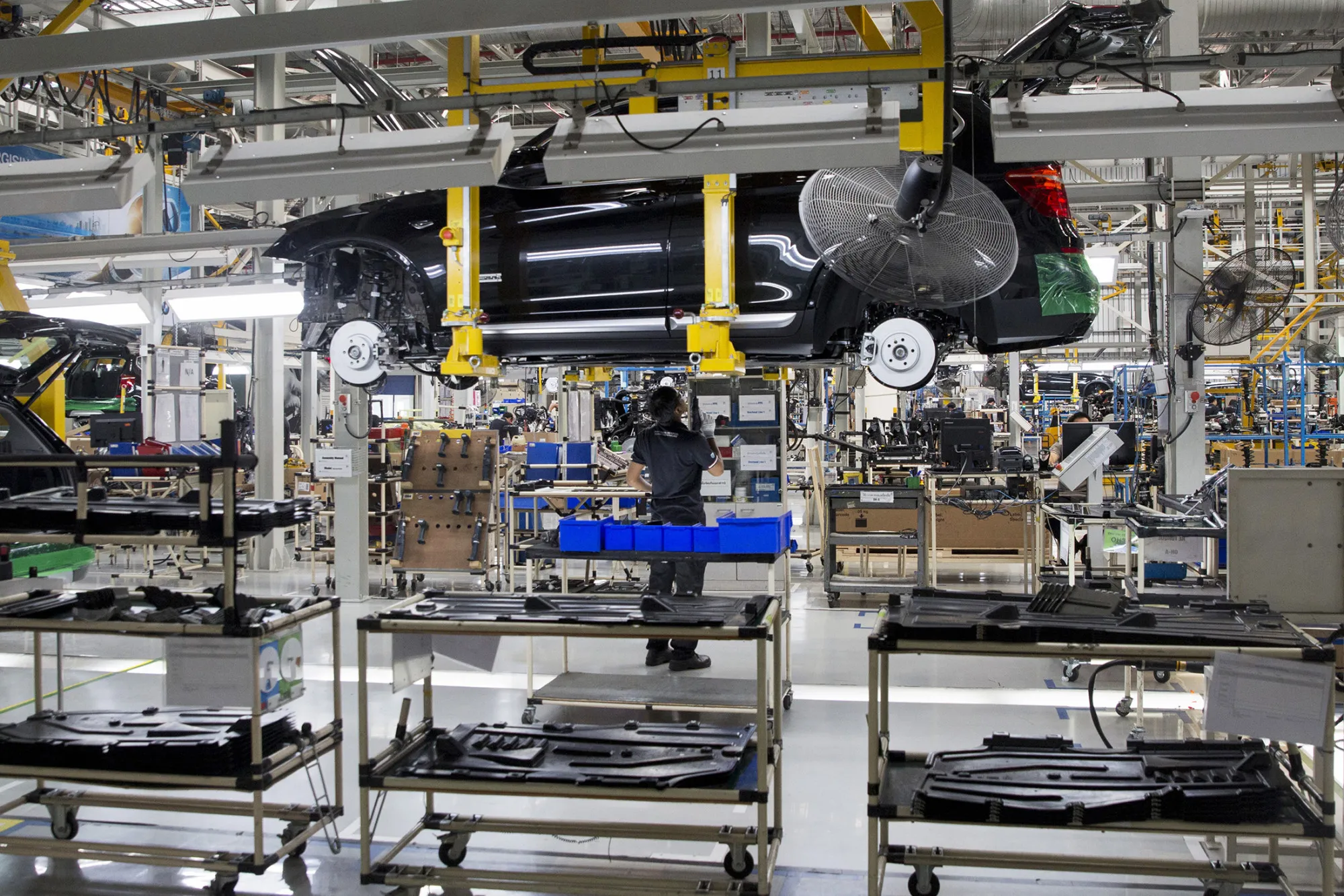 A worker prepares to drill a bolt In to a BMWX5 xDrive40e M Sport plug-in hybrid vehicle supported by an overhead crane at the BMW AG assembly plant in Amata, Rayong province, Thailand on Feb. 1, 2017.
