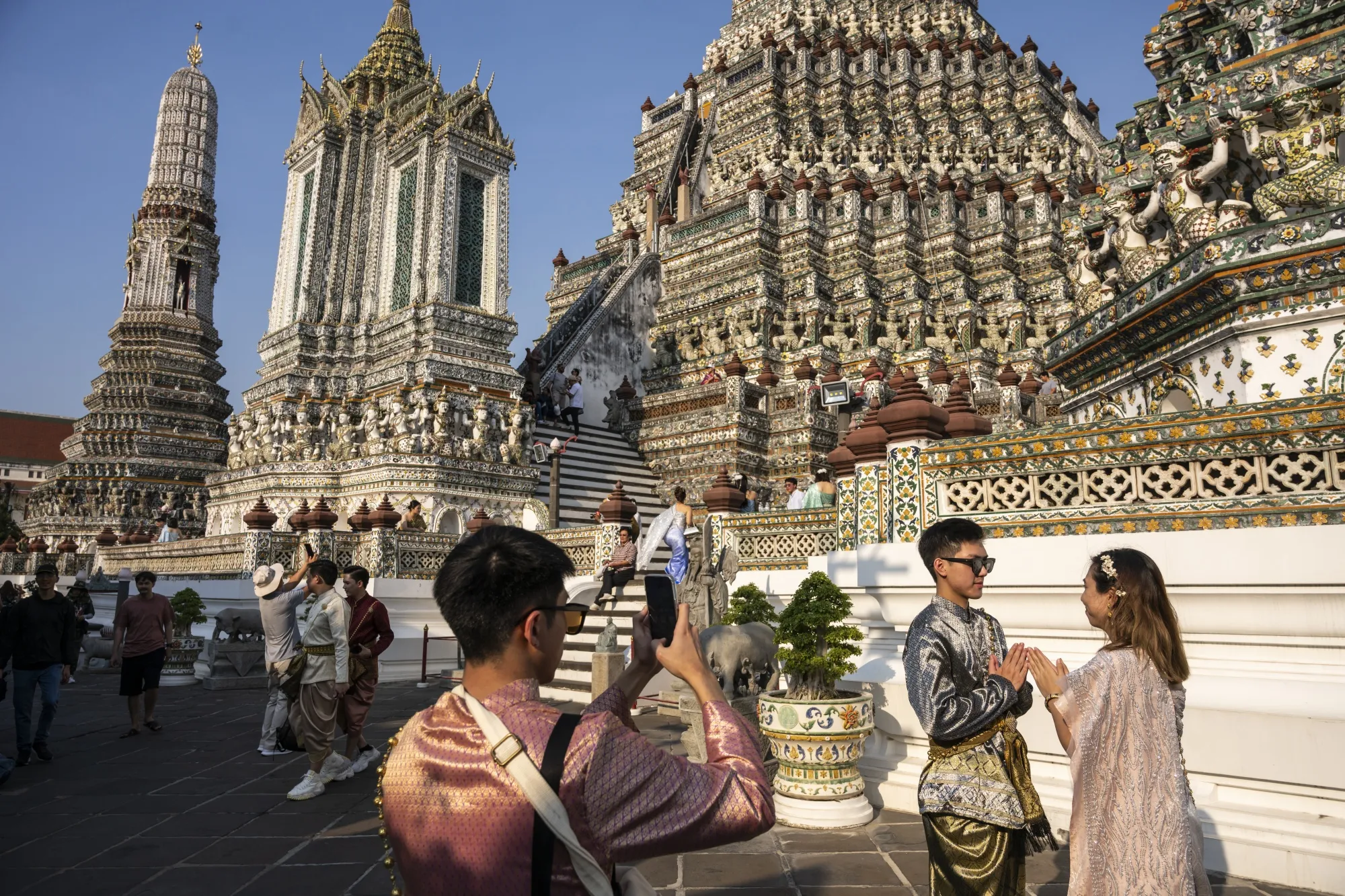 Chinese tourists in Thai traditional dress pose for photographs at Wat Arun Ratchawararam Rathawaramahawihan in Bangkok.