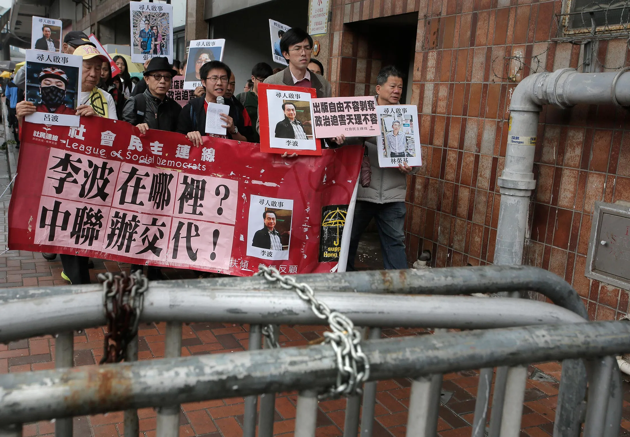 Protesters hold photos of missing booksellers during a protest outside the Liaison of the Central People's Government in Hong Kong, Sunday, Jan. 3, 2016. Hong Kong pro-democracy lawmakers say they'll press the government for answers after a fifth employee of a publisher specializing in books critical of China's ruling communists went missing. The Chinese words on banner reads 'Where is Lee Bo? Liaison of the Central People's Government of Hong Kong explain!'
