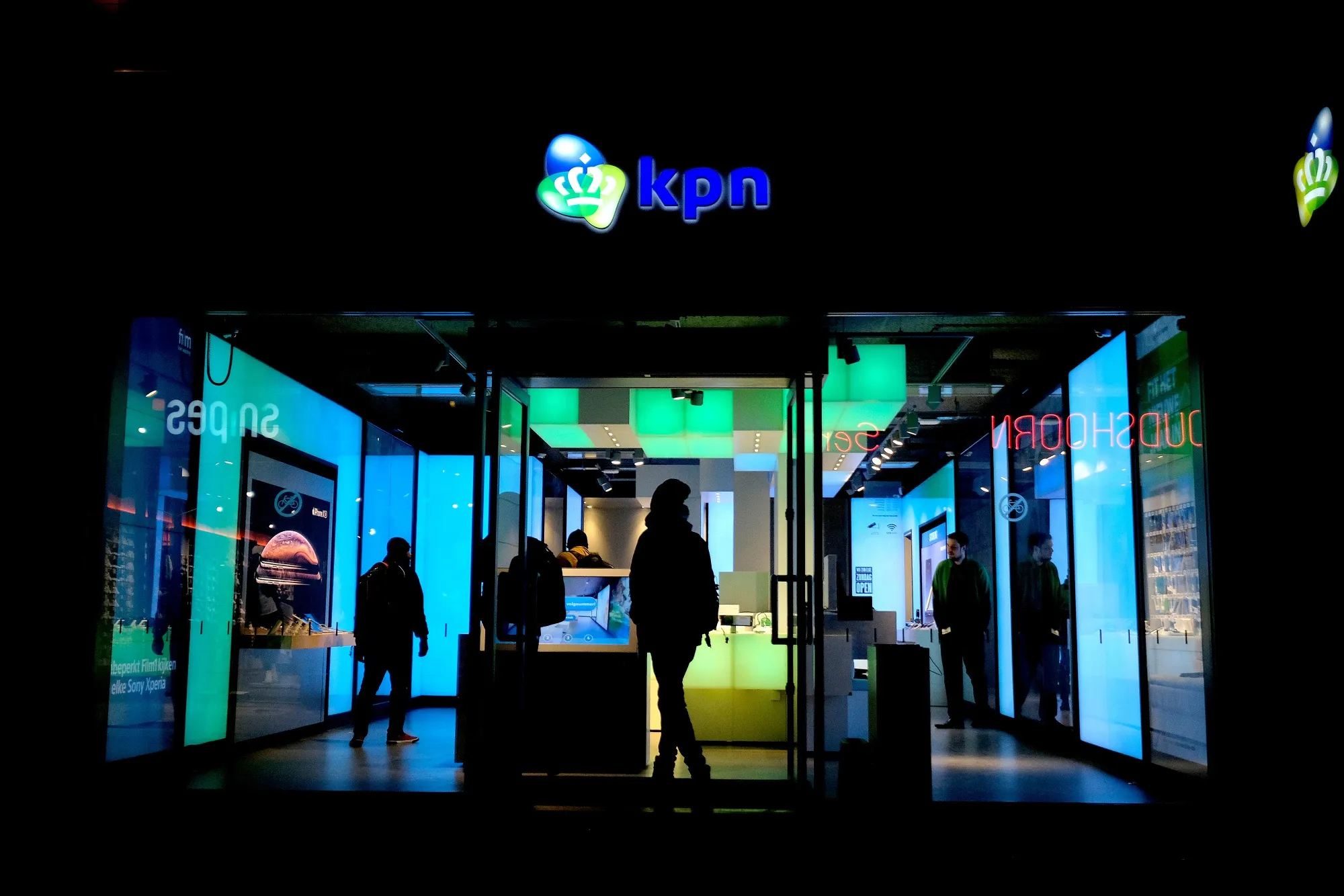 Customers browse inside a Royal KPN NV mobile phone store at night in Leiden, Netherlands.