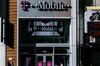 Pedestrians pass in front of a T-Mobile US Inc. store in New York.