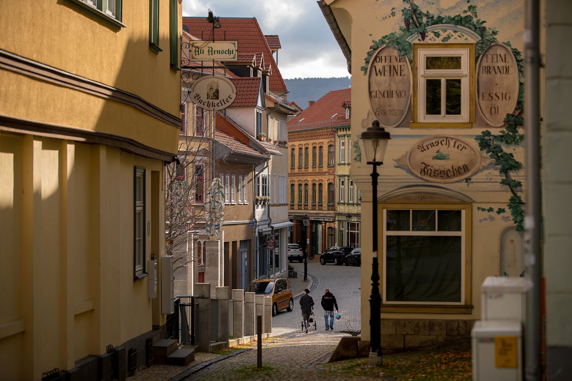 Pedestrians walk along a cobbled street near restaurants in Arnstadt.
