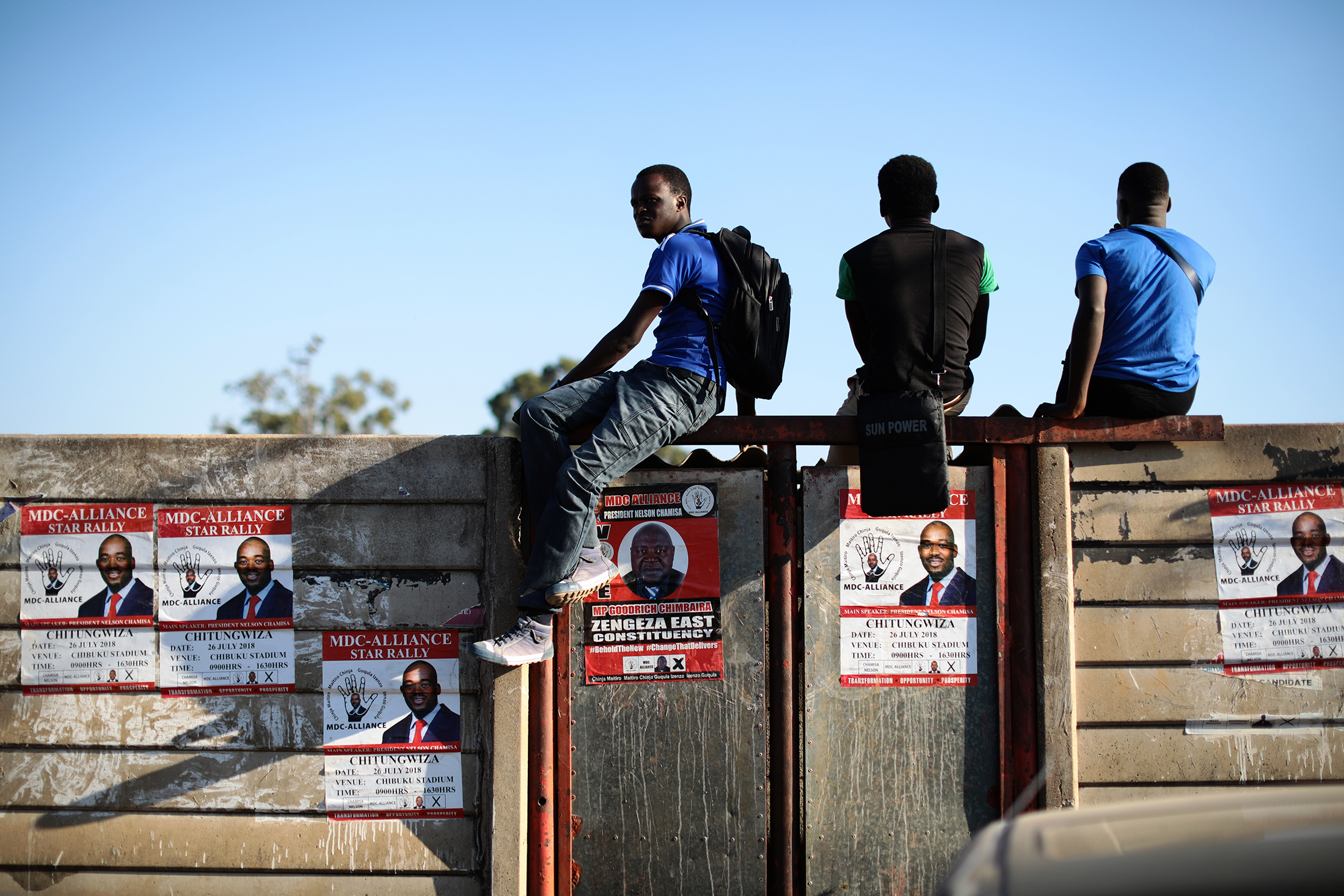 Election&nbsp;posters hang on a wall as people watch MDC-Alliance (Movement for Democratic Change) leader and opposition presidential candidate Nelson Chamisa speaking during a rally on July 26, 2018 in Chitungwiza, Zimbabweans.