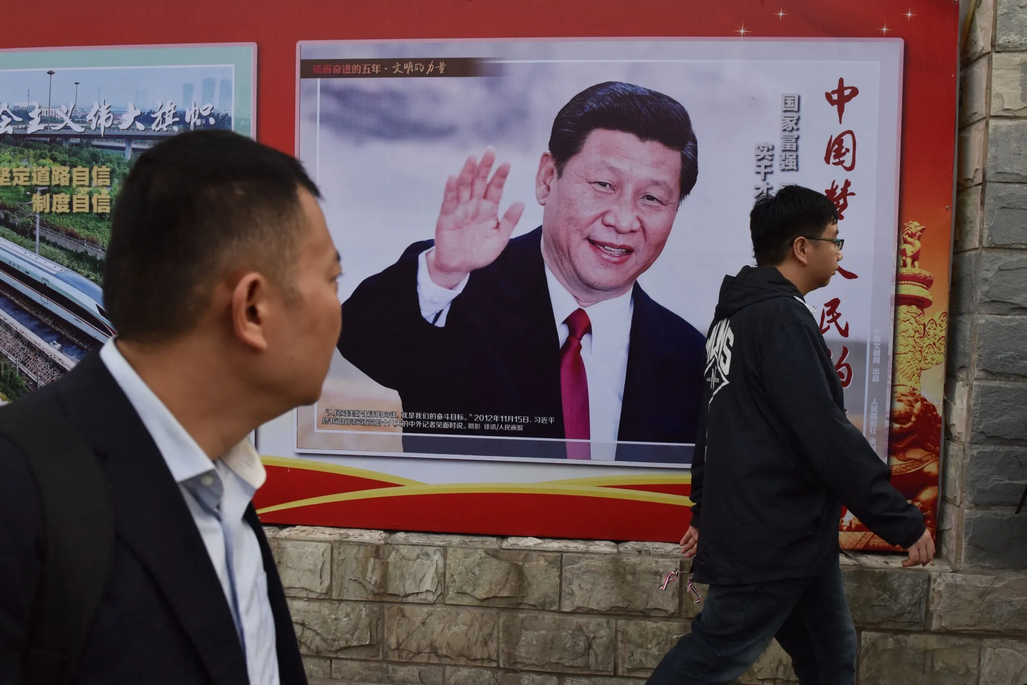 People walk past a poster featuring Chinese President Xi Jinping with a slogan reading “Chinese Dream, People’s Dream”&nbsp;beside a road in Beijing on Oct.&nbsp;16, 2017.&nbsp;&nbsp;