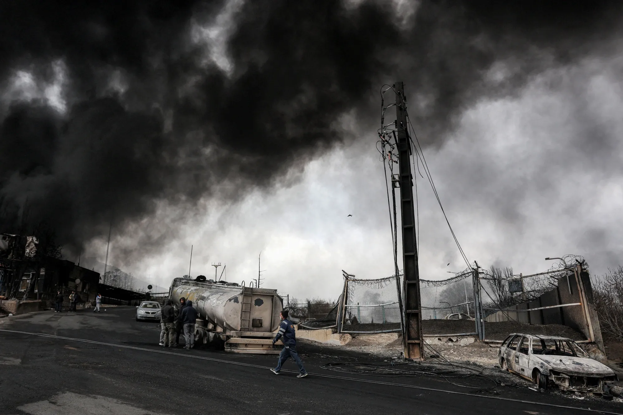 Smoke engulfs destroyed vehicles on March 8 in Tehran, following an overnight airstrike on the Shahran oil refinery.