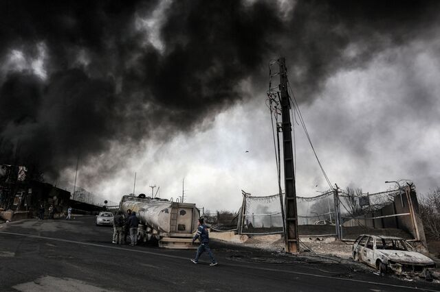 Smoke engulfs destroyed vehicles on March 8 in Tehran, following an overnight airstrike on the Shahran oil refinery. 