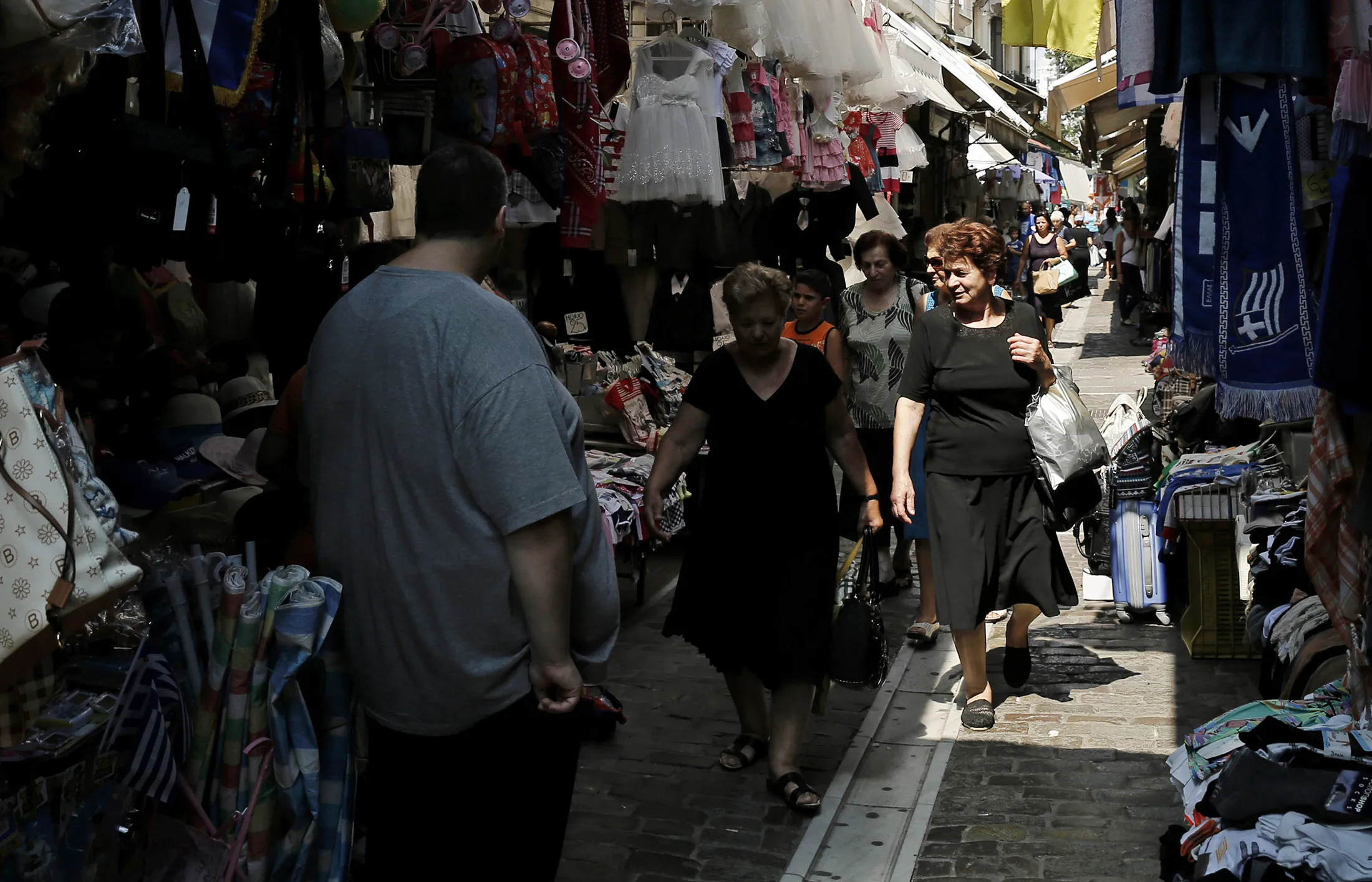 Pedestrians walk through a street market in Thessaloniki, Greece.
