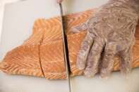 An employee prepares portions of salmon fillet 