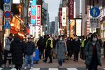 Pedestrians wearing protective face masks pass bars and restaurants in the Shimbashi District of Tokyo.