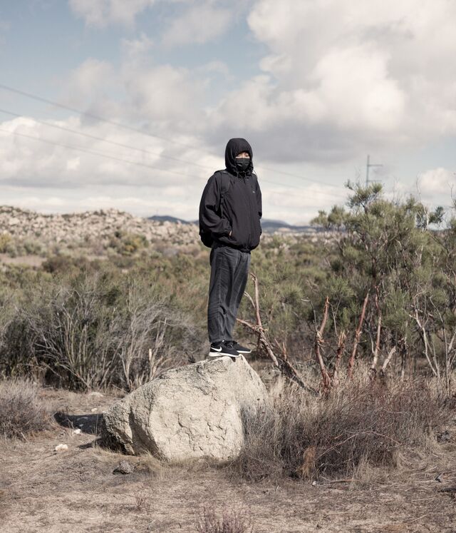 A portrait of Axiu , a 30-year old asylum seeker from China, stands on a rock in the desert. 