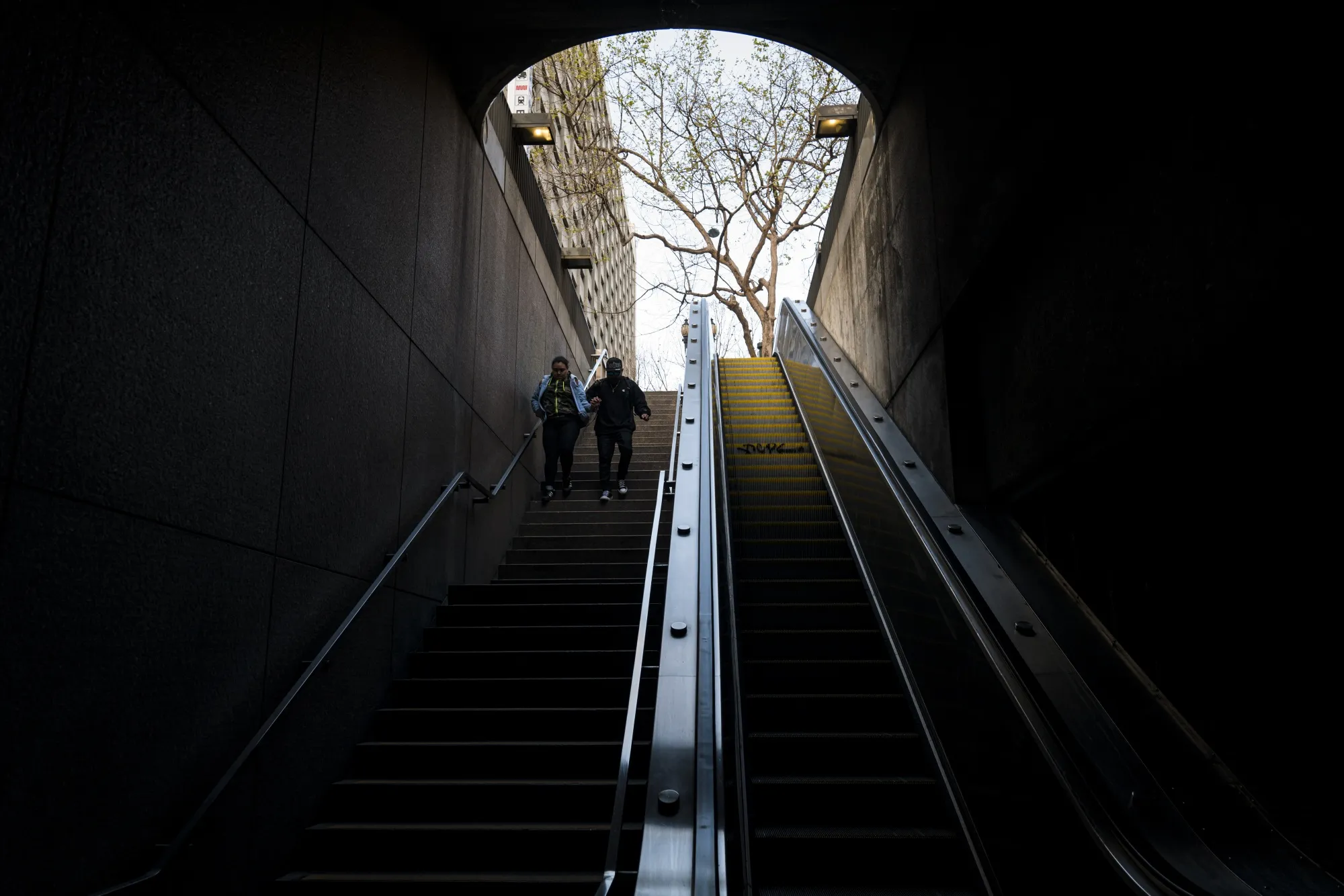 Pedestrians walk down a staircase to a Bay Area Rapid Transit station in San Francisco on March 26.