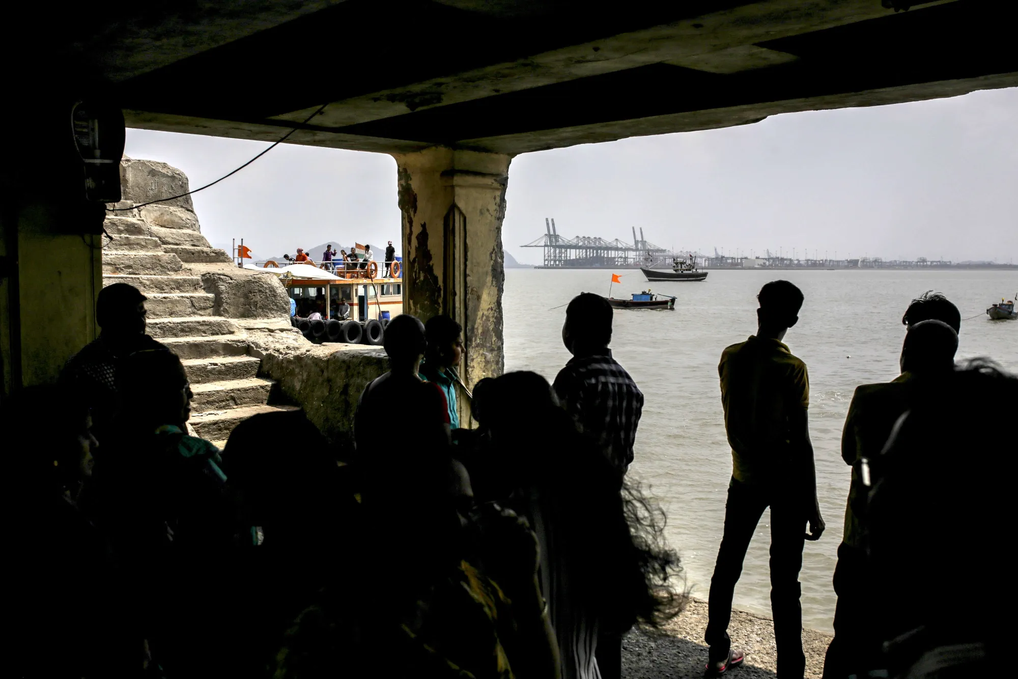 People stand at a pier as gantry cranes&nbsp;stand in the distance at the Jawaharlal Nehru Port in Navi Mumba.