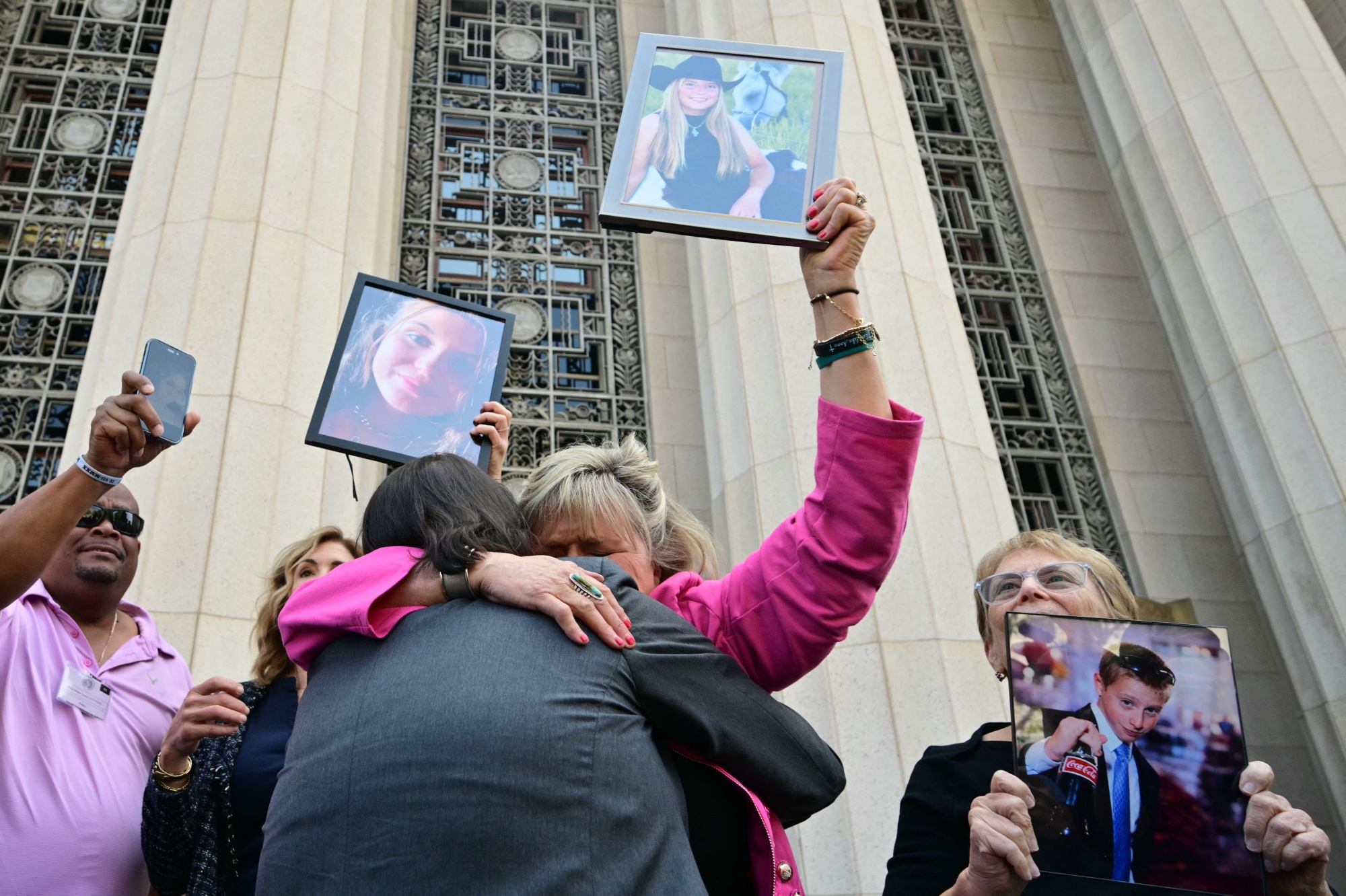 Relatives of victims, including Lori Schott, center, walk out of the Los Angeles Superior Court holding portraits of their loved ones in Los Angeles, on March 25, 2026. A Los Angeles jury on Wednesday found Meta and YouTube liable for harming a young woman through the addictive design of their social media platforms and ordered the companies to pay $3 million in damages.
