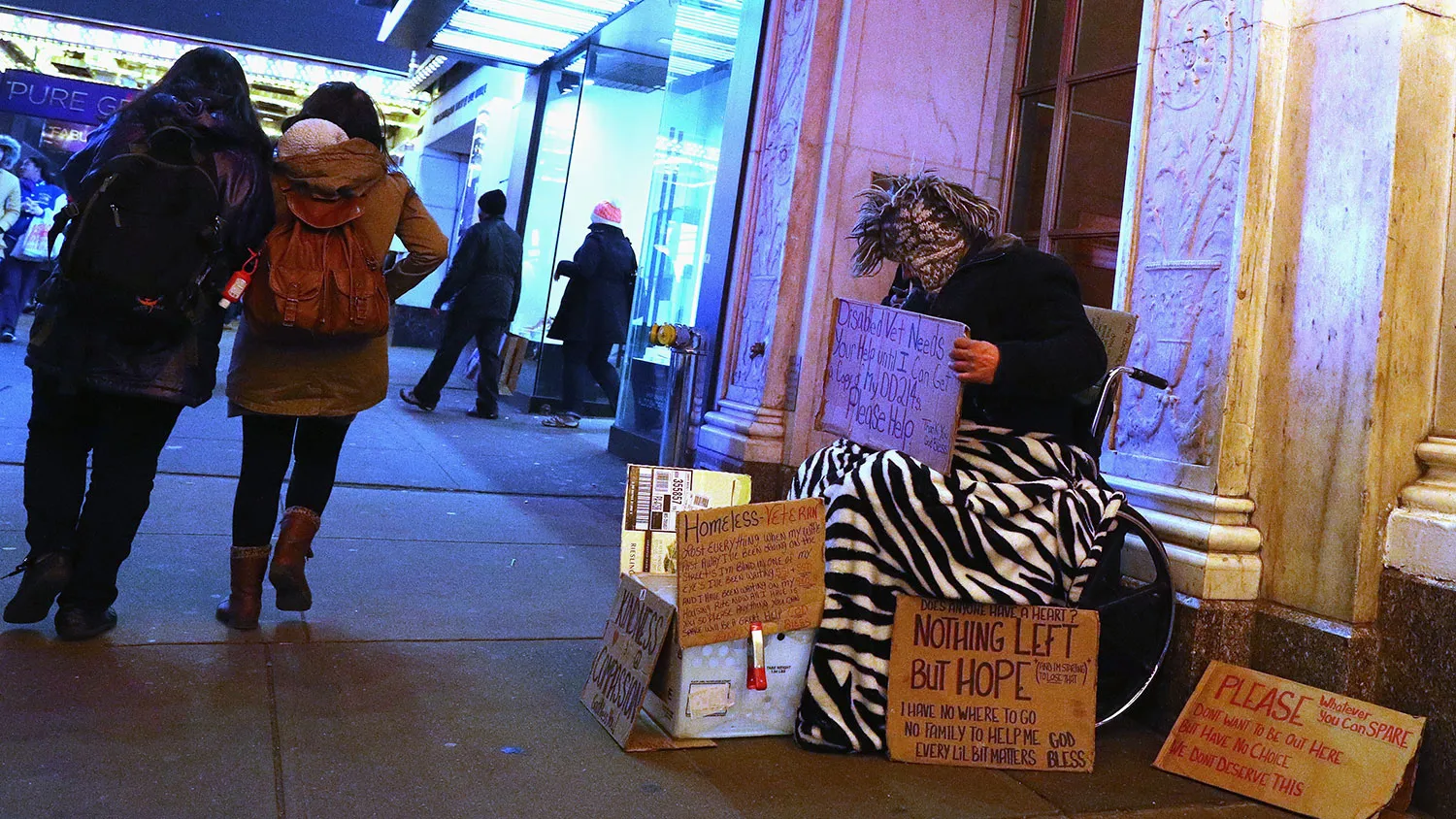 A homeless person sits as tourists walk through Times Square on March 5, 2016, in New York City.
