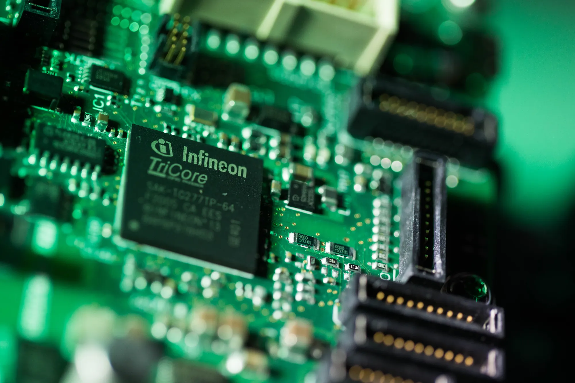 An Infineon TriCore microcontroller computer circuit component sits beside circuitry on an Infineon HybridPACK automotive drive evaluation kit.
