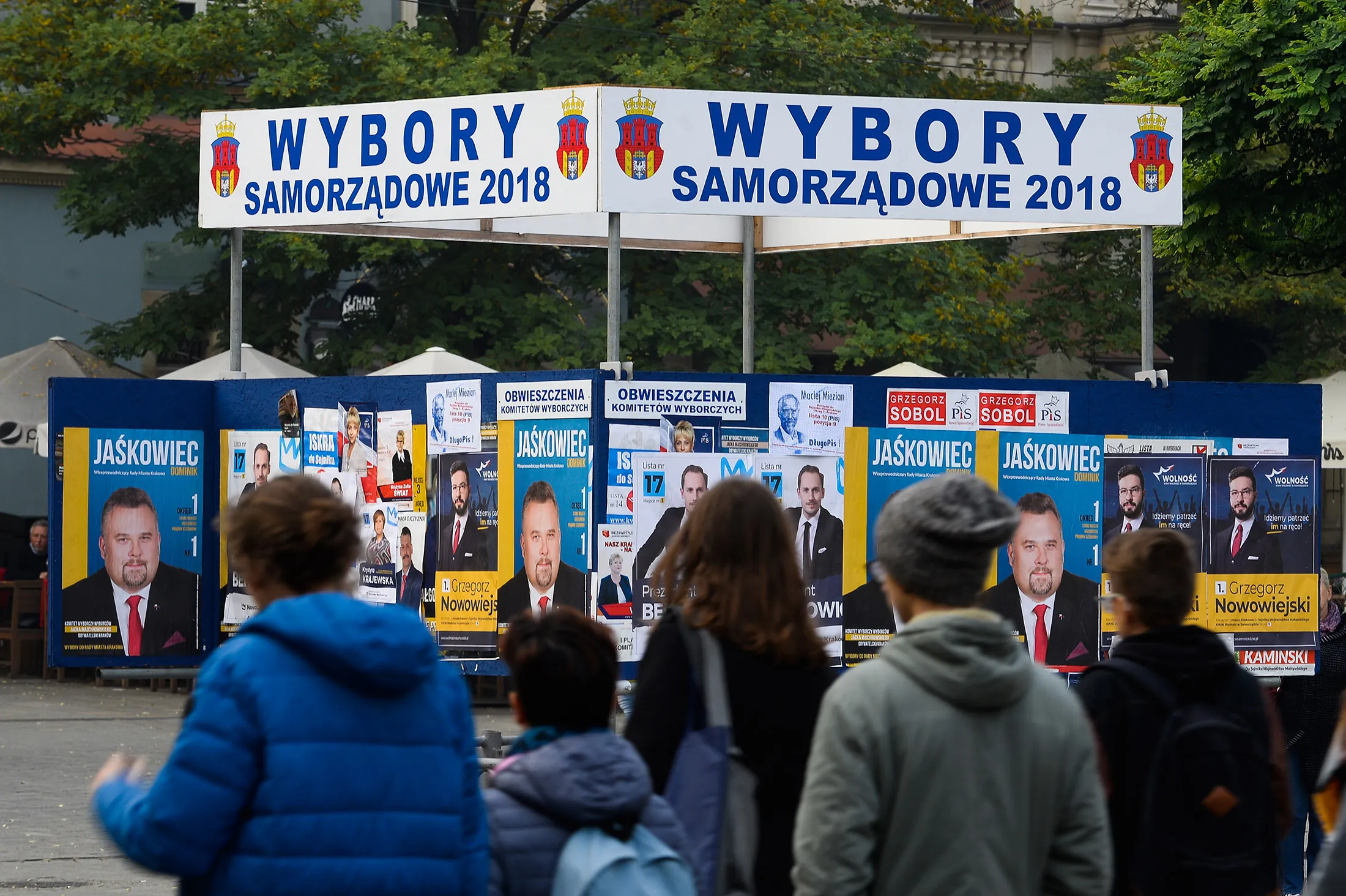 Polish citizens stand while looking at a sign board with